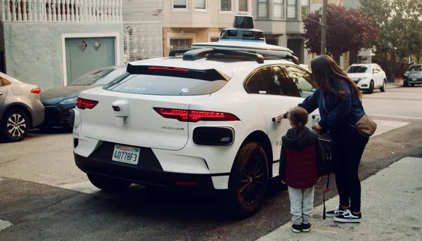 A mother and child approaching a white Waymo self-driving car with roof-mounted sensors on a San Francisco street